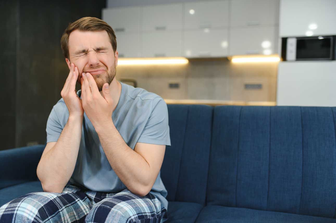 Young adult holding his cheek because of dental pain